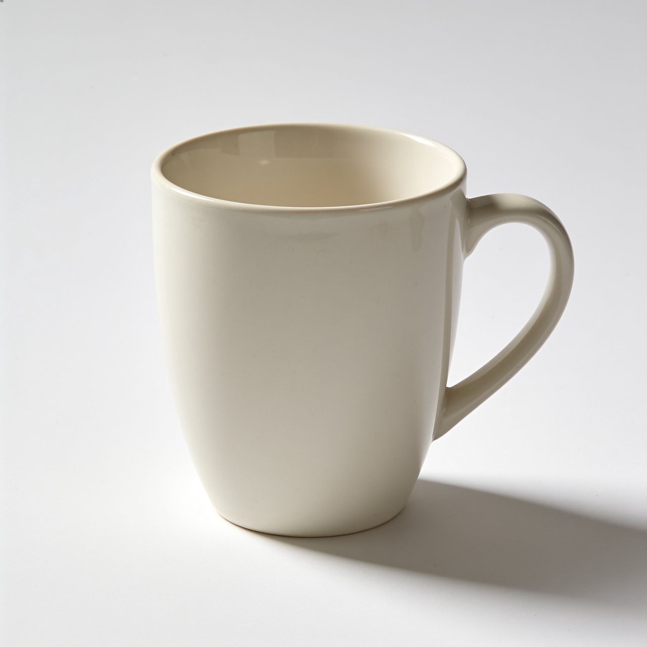 Plain off-white ceramic mug with a handle on a white background.
